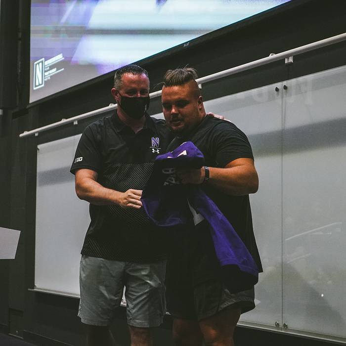 Defensive lineman Joe Spivak receives the No. 1 jersey from head coach Pat Fitzgerald.