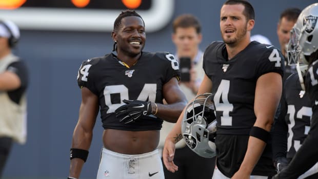 Oakland Raiders wide receiver Antonio Brown (84) and quarterback Derek Carr (4) hold their helmets before a game against the Green Bay Packers at Investors Group Field.