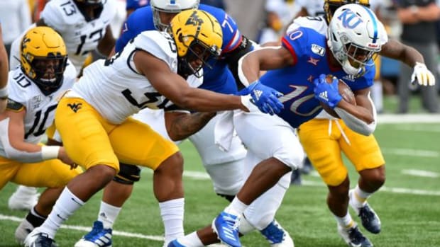 LAWRENCE, KANSAS - SEPTEMBER 21:  Running back Khalil Herbert #10 of the Kansas Jayhawks tries to avoid a tackle by linebacker Josh Chandler #35 of the West Virginia Mountaineers in the first quarter at Memorial Stadium on September 21, 2019 in Lawrence, Kansas. (Photo by Ed Zurga/Getty Images)