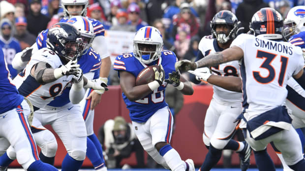 Buffalo Bills running back Devin Singletary (26) runs between Denver Broncos defensive end Derek Wolfe (95) and free safety Justin Simmons (31) in the first quarter at New Era Field.