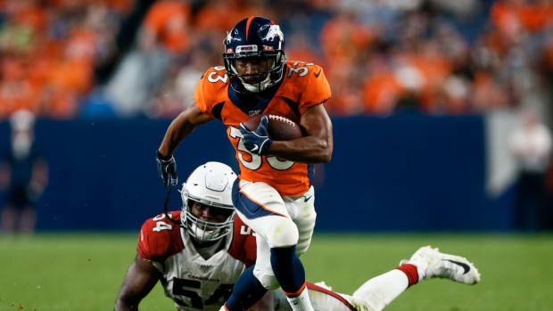 Denver Broncos running back Khalfani Muhammad (33) runs through the tackle of Arizona Cardinals linebacker Vontarrius Dora (54) in the fourth quarter at Broncos Stadium at Mile High.