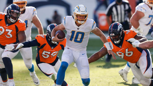 Los Angeles Chargers quarterback Justin Herbert (10) runs the ball as Denver Broncos defensive end Shelby Harris (96) and linebacker Malik Reed (59) defend in the first quarter at Empower Field at Mile High.