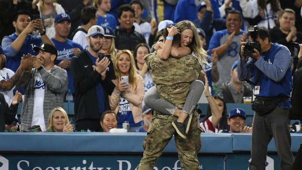 Apr 20, 2018; Los Angeles, CA, USA; Jordan Wolfe embraces her husband, U.S. Air Force Capt. Robert Wolfe (back to camera) during the second inning of a game between the Los Angeles Dodgers and the Washington Nationals at Dodger Stadium. Capt. Wolfe, currently serving a six-month deployment in Afghanistan was recognized as the Military Hero of the Game and surprised his wife by showing up. Mandatory Credit: Richard Mackson-USA TODAY Sports