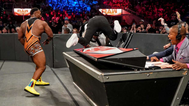 Big E throws his opponent through the announcers' table