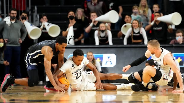 Cincinnati Bearcats guard Mika Adams-Woods (23) competes for possession of a loose ball against Monmouth Hawks guard Marcus McClary (13) in the second half of an NCAA men s college basketball game, Saturday, Nov. 27, 2021, at Fifth Third Arena in Cincinnati. The Monmouth Hawks won, 61-59. Monmouth Hawks At Cincinnati Bearcats Nov 27