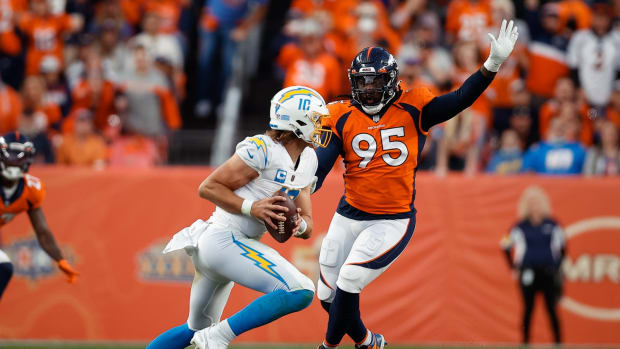 Los Angeles Chargers quarterback Justin Herbert (10) looks to pass under pressure from Denver Broncos defensive tackle McTelvin Agim (95) in the third quarter at Empower Field at Mile High.