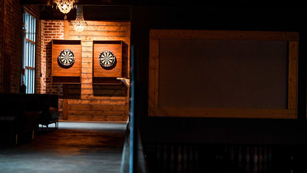 Dart boards can be seen in a hallway next to the bowling alley