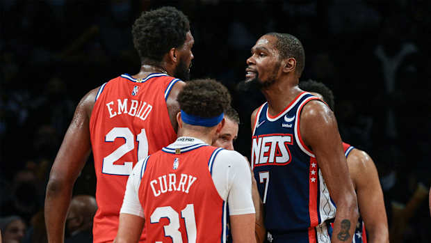 Dec 30, 2021; Brooklyn, New York, USA; Philadelphia 76ers center Joel Embiid (21) exchanges words with Brooklyn Nets forward Kevin Durant (7) in front of guard Seth Curry (31) during the second half at Barclays Center.