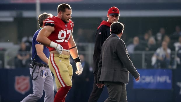 San Francisco 49ers defensive end Nick Bosa walks off the field with team medical staff.