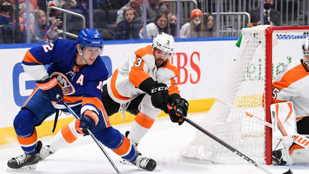 Jan 17, 2022; Elmont, New York, USA; New York Islanders right wing Josh Bailey (12) looks to pass from behind the net defended by Philadelphia Flyers defenseman Keith Yandle (3) during the second period at UBS Arena. Mandatory Credit: Dennis Schneidler-USA TODAY Sports