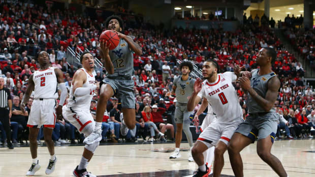 Jan 22, 2022; Lubbock, Texas, USA; West Virginia Mountaineers guard Taz Sherman (12) goes to the basket between Texas Tech Red Raiders guard Kevin Obanor (0) and forward Marcus Santos-Silva (14) in the second half at United Supermarkets Arena.