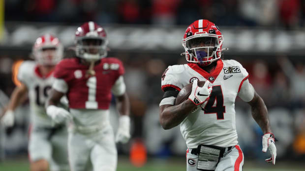 Georgia Bulldogs running back James Cook (4) runs the ball against Alabama Crimson Tide defensive back Kool-Aid McKinstry (1) during the third quarter of the 2022 CFP college football national championship game at Lucas Oil Stadium.