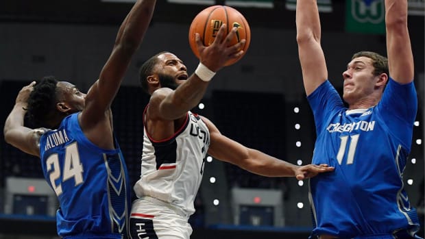 Connecticut's R.J. Cole shoots between Creighton's Arthur Kaluma (24) and Creighton's Ryan Kalkbrenner (11) in the first half of an NCAA college basketball game, Tuesday, Feb. 1, 2022, in Hartford, Conn.