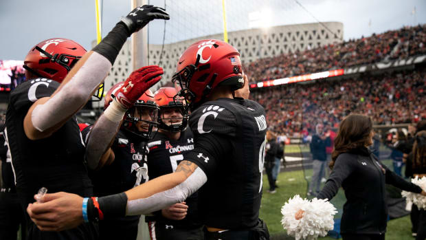Cincinnati Bearcats quarterback Desmond Ridder (9) celebrates with Cincinnati Bearcats tight end Josh Whyle (81) and Cincinnati Bearcats running back Ryan Montgomery (22) after scoring a touchdown in the first half of the NCAA football game between the Cincinnati Bearcats and the Southern Methodist Mustangs on Saturday, Nov. 20, 2021, at Nippert Stadium in Cincinnati. Southern Methodist Mustangs At Cincinnati Bearcats 23
