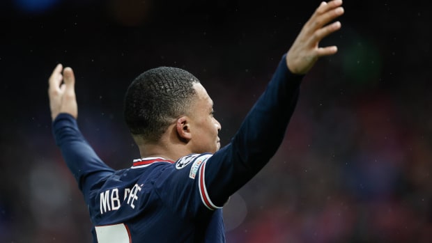 Kylian Mbappe celebrates with his arms raised after scoring for PSG against Real Madrid in February 2022