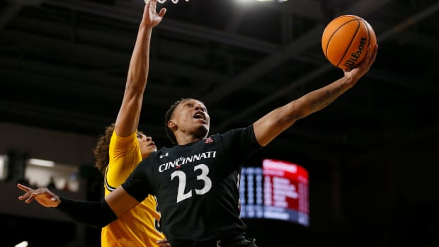 Cincinnati Bearcats guard Mika Adams-Woods (23) lays up a shot ahead of Wichita State Shockers guard Craig Porter Jr. (3) in the first half of the NCAA American Athletic Conference basketball game between the Cincinnati Bearcats and the Wichita State Shockers at Fifth Third Arena in Cincinnati on Thursday, Feb. 17, 2022. The Bearcats led 42-35 at halftime. Wichita State Shockers At Cincinnati Bearcats Basketball