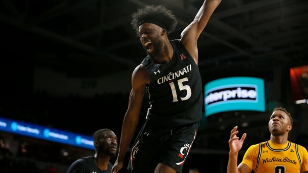 Cincinnati Bearcats forward John Newman III (15) swings around the rim after a dunk in the second half of the NCAA American Athletic Conference basketball game between the Cincinnati Bearcats and the Wichita State Shockers at Fifth Third Arena in Cincinnati on Thursday, Feb. 17, 2022. The Bearcats carried a halftime lead to win 85-76 in the conference matchup. Wichita State Shockers At Cincinnati Bearcats Basketball