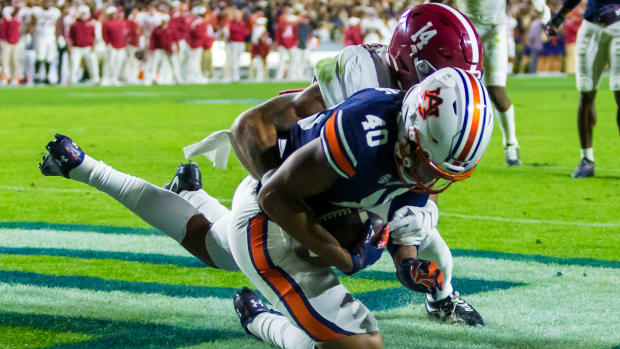 Auburn tight end Landen King (40) makes a one-handed grab to score a touchdown despite Alabama defensive back Brian Branch (14) holding his left arm during the first overtime of an NCAA college football game, Saturday, Nov. 27, 2021, in Auburn, Ala. The touchdown sent the game to a second overtime, a game won in four overtimes by Alabama, 24-22.