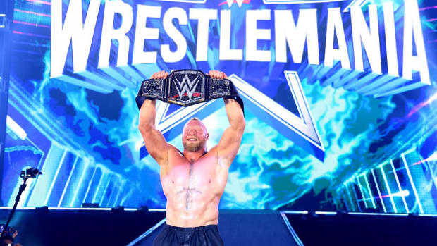 Brock Lesnar holds up the WWE champion belt after wrestling in the Elimination Chamber.