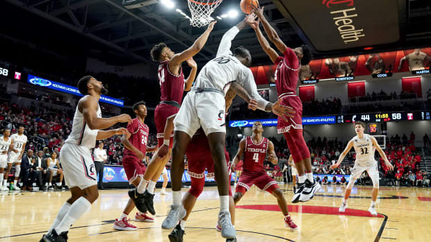 Cincinnati Bearcats forward Abdul Ado (00) competes for a rebound against Temple Owls forward Zach Hicks (24), left, and Temple Owls forward Sage Tolbert III (3), right, in the second half of an NCAA basketball game, Sunday, Feb. 20, 2022, at Fifth Third Arena in Cincinnati. The Temple Owls won, 75-71. Temple Owls At Cincinnati Bearcats Basketball Feb 20 Seqn