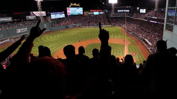 MLB fans silhouetted against the backdrop of Fenway Park