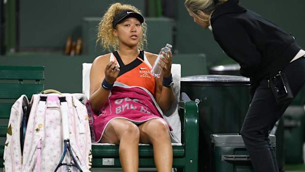 Naomi Osaka talks to an official on the sideline.