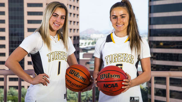 Haley and Hanna Cavinder pose for a photo while holding basketballs.