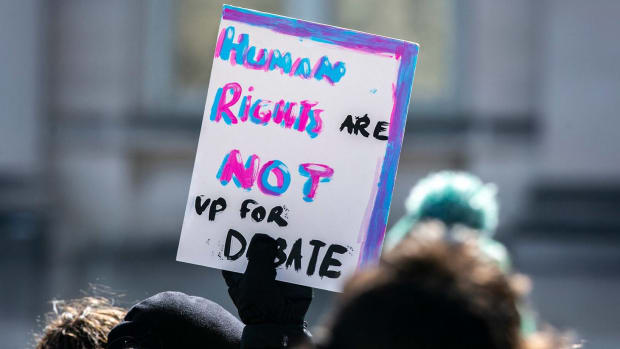 Someone holding a sign that says "Human Rights Are Not Up For Debate."