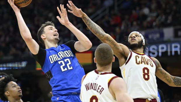 Mar 28, 2022; Cleveland, Ohio, USA; Orlando Magic forward Franz Wagner (22) drives to the basket beside Cleveland Cavaliers guard Dylan Windler (9) and forward Lamar Stevens (8) in the third quarter at Rocket Mortgage FieldHouse. Mandatory Credit: David Richard-USA TODAY Sports