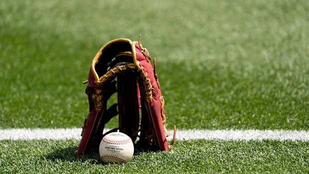 A glove and a baseball on a field.