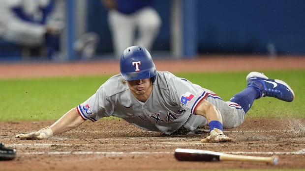 Apr 10, 2022; Toronto, Ontario, CAN; Texas Rangers left fielder Nick Solak (15) slides into home plate to score against the Toronto Blue Jays during the fifth inning at Rogers Centre. Mandatory Credit: John E. Sokolowski-USA TODAY Sports