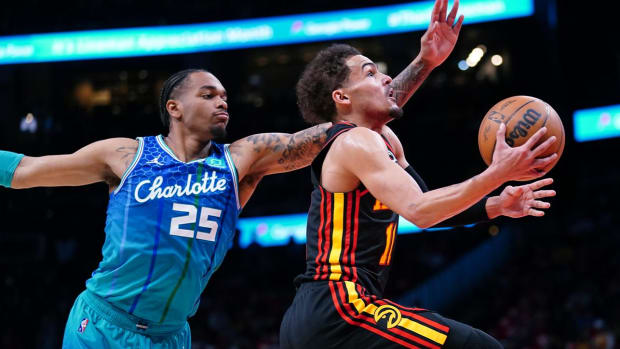 Atlanta Hawks guard Trae Young (11) drives to the basket past Charlotte Hornets forward P.J. Washington (25) during the first half of an NBA play-in basketball game Wednesday, April 13, 2022, in Atlanta.