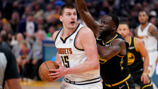 Denver Nuggets center Nikola Jokic (15) controls the ball against Golden State Warriors forward Draymond Green.