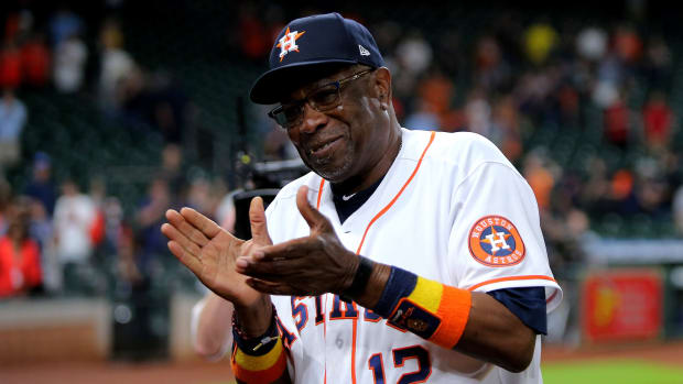 Astros manager Dusty Baker claps to the fans while walking off the field.