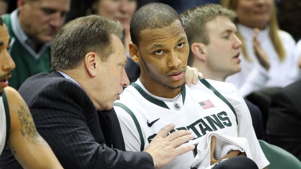 Michigan State men’s basketball coach Tom Izzo (left) talks to center Adreian Payne (5) on the bench during a game.