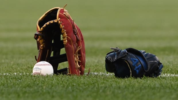 A baseball and two gloves rest on the field.