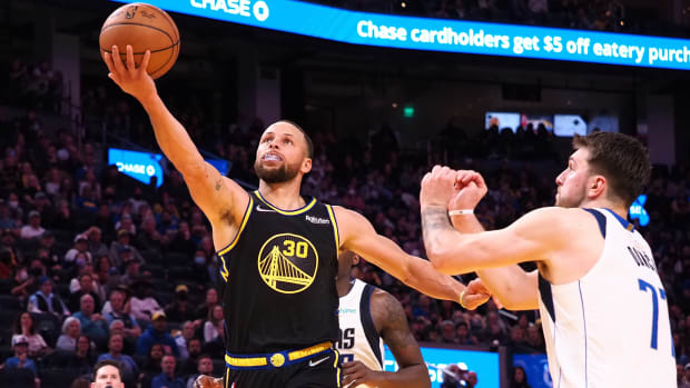 Golden State Warriors guard Stephen Curry (30) goes up for a shot against Dallas Mavericks guard Luka Doncic.