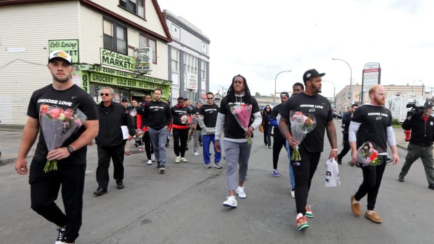 Members of the Buffalo Bills walk to the site of the last Saturday's mass shooting at the Tops supermarket in Buffalo. After visiting the site, the team helped distribute food to members of the community.