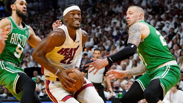 Miami Heat forward Jimmy Butler (22) drives to the basket between Boston Celtics guard Derrick White (9) and center Daniel Theis (27) during the second half of Game 1 of an NBA basketball Eastern Conference finals playoff series, Tuesday, May 17, 2022, in Miami.