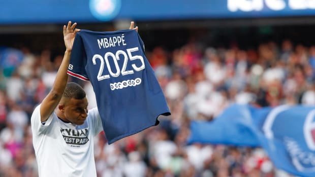 Kylian Mbappe pictured holding up a jersey reading "Mbappe 2025" after signing his new PSG contract in May 2022