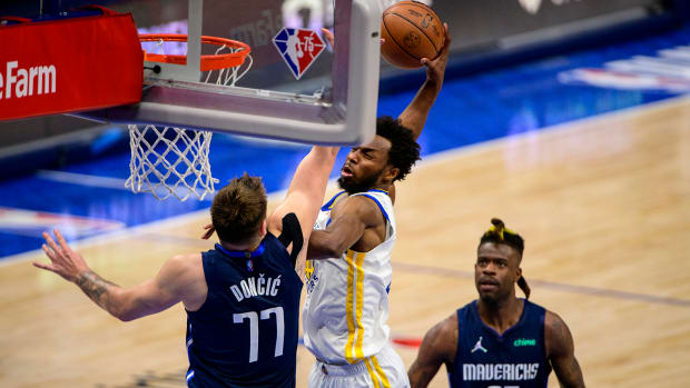 Golden State Warriors forward Andrew Wiggins (22) dunks the ball over Dallas Mavericks guard Luka Doncic.