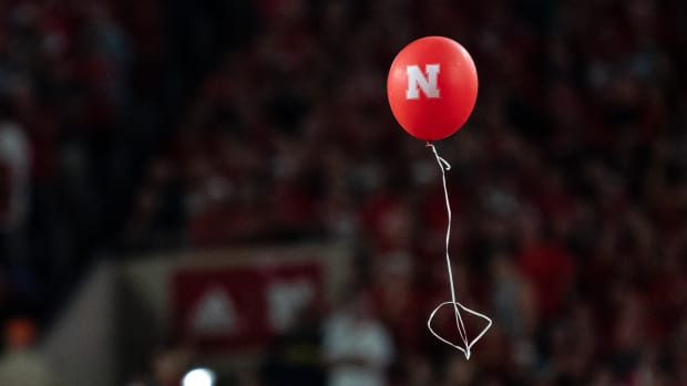 A red Nebraska Cornhuskers balloon floats down onto the field during a game.