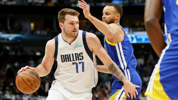 Dallas Mavericks guard Luka Doncic (77) dribbles the ball against Golden State Warriors guard Stephen Curry.