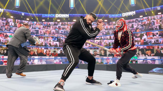 Rey Mysterio hits Roman Reigns with a kendo stick