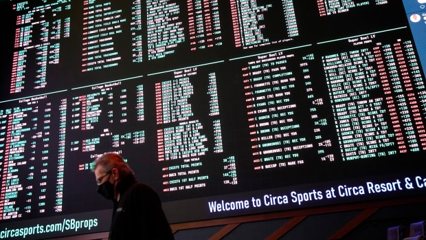 FILE - A man walks by as betting odds for NFL football's Super Bowl 55 are displayed on monitors at the Circa resort and casino sports book in Las Vegas, Feb. 3, 2021. Las Vegas oddsmakers had argued for years that sports betting is easier to monitor where it's legal and regulated. (AP Photo/John Locher, File)