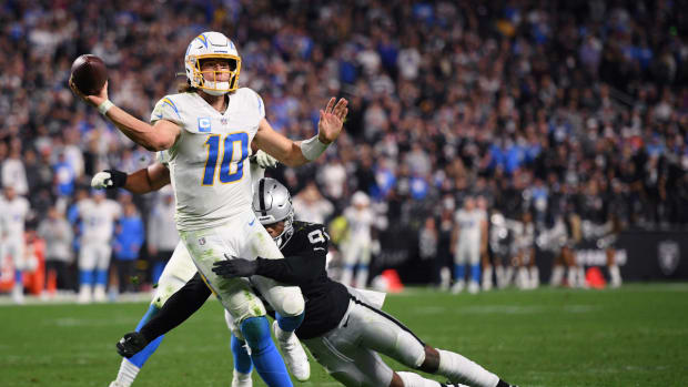 Jan 9, 2022; Paradise, Nevada, USA; Los Angeles Chargers quarterback Justin Herbert (10) throws a pass for a two-point conversion while tackled by Las Vegas Raiders defensive end Yannick Ngakoue (91) during the second half at Allegiant Stadium. Mandatory Credit: Orlando Ramirez-USA TODAY Sports