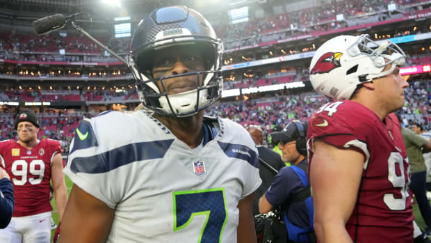 Seattle Seahawks quarterback Geno Smith wears a helmet surrounded by Cardinals players