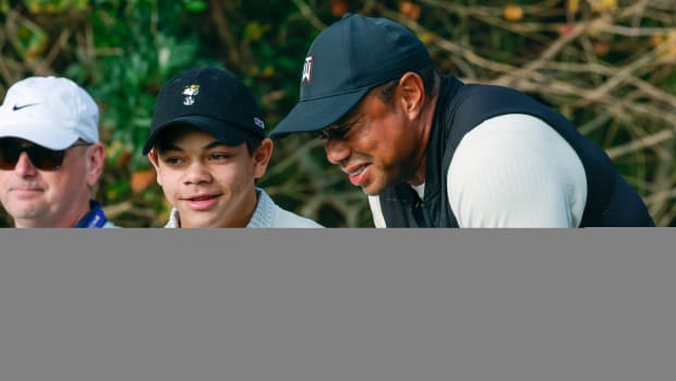 Charlie Woods and Tiger Woods talk on the first tee box before the first hole during a pro-am round of the PNC Championship golf tournament.