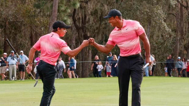 Charlie Woods and father Tiger Woods fist bump after a birdie on the ninth hole during the first round of the PNC Championship.