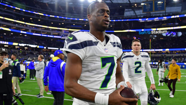 Seattle Seahawks quarterback Geno Smith walks off the field with no helmet on holding a ball